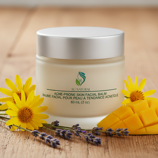 A jar of AU NATURAL Acne-Prone Skin Facial Balm with a silver lid and white container, styled on a wooden surface with yellow flowers, lavender sprigs, and sliced mango.